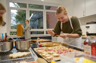 Am Ende wird's bunt: Die Schülerinnen und Schüler überziehen die Plätzchen mit rotem Guss und dekorieren sie mit farbigen Perlen. Foto: SMMP/Ulrich Bock